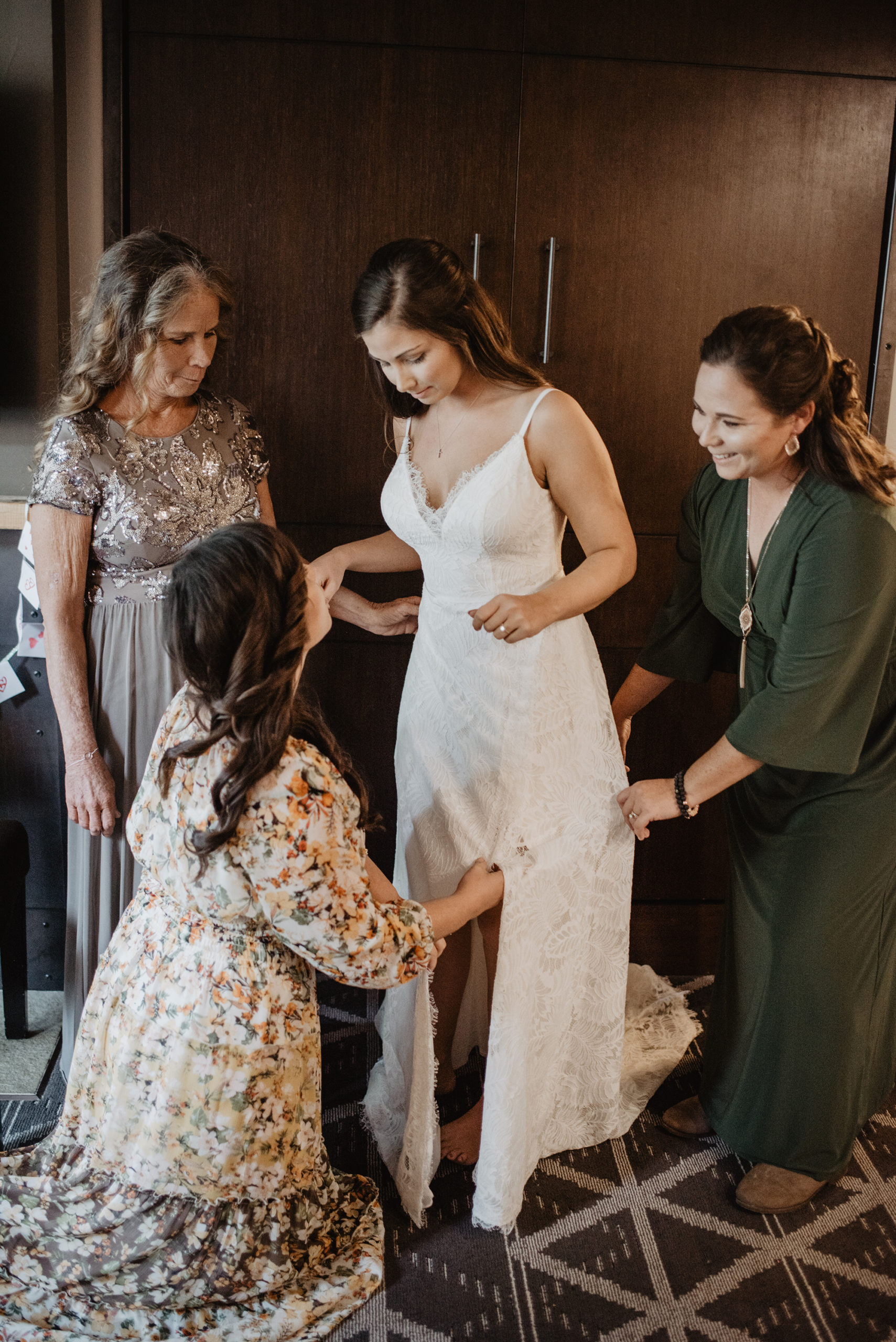 bride getting into her wedding dress the morning of her elopement in the Grand Tetons with her mother and friends helping her