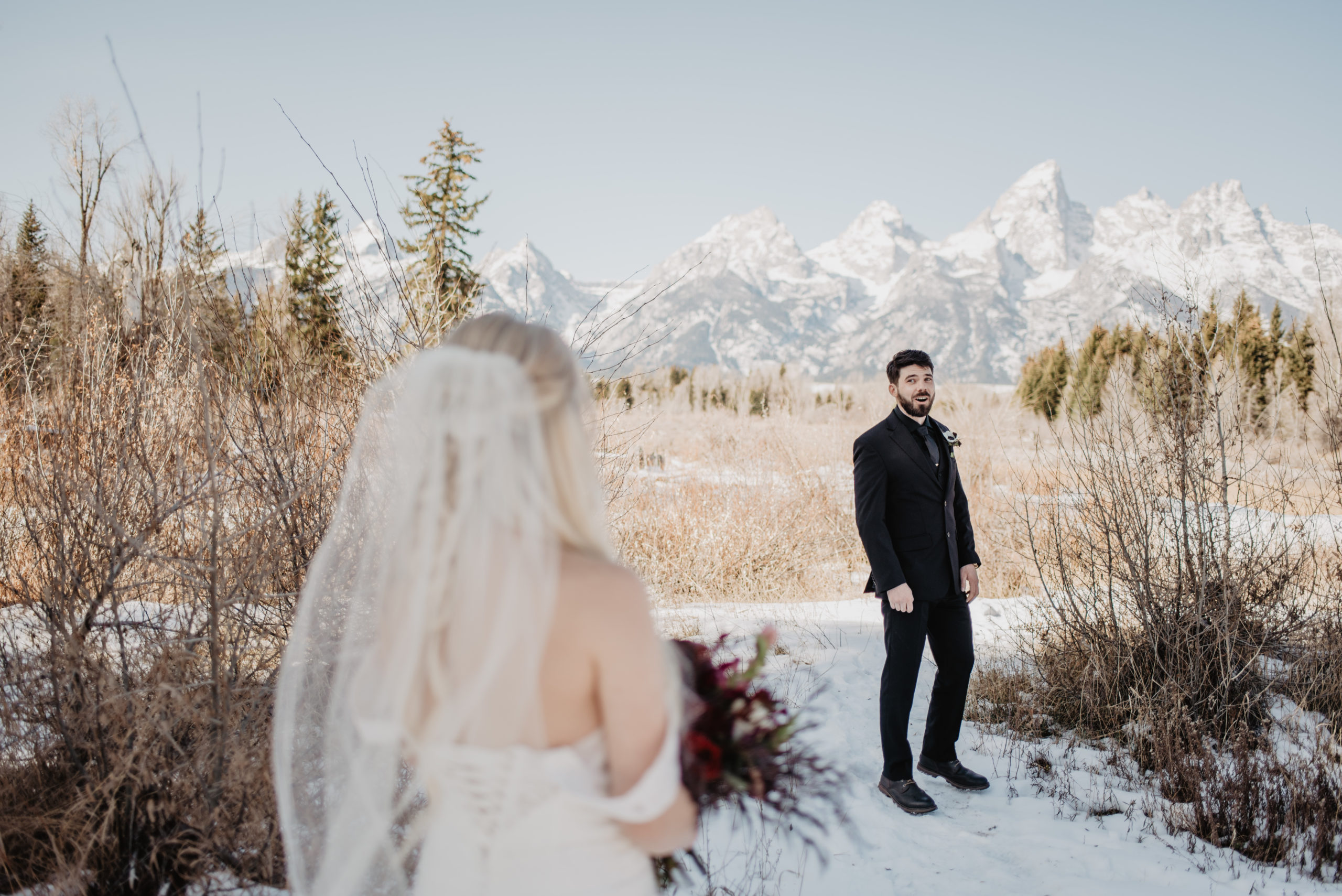 winter elopement in Jackson Hole, first look and groom in blown away and super expressive with the Grand Tetons behind him covered in snow