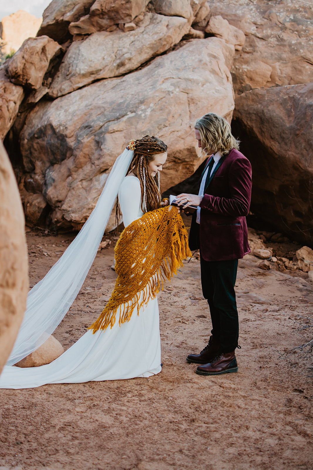 bride and groom standing face to face while they read their vows to each other for their fall bohemian elopement
