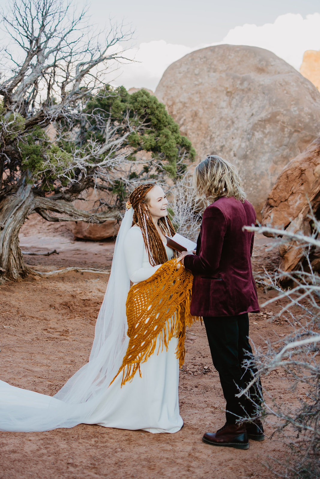 bride and groom standing in the red rocks in the Arches sharing their vows together before their elopement ceremony capture by the best Moab wedding photographers with fall bridals