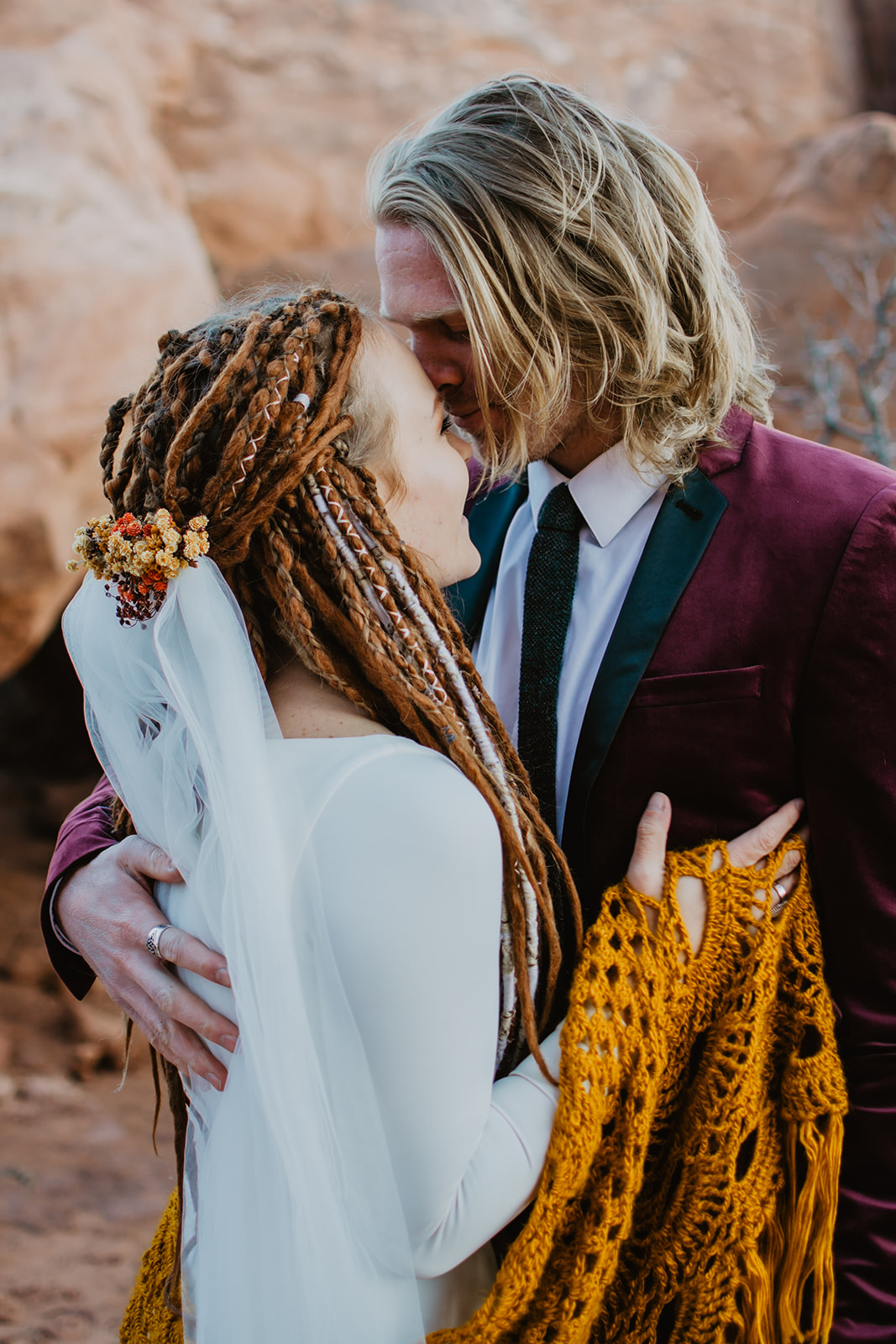 eloping in Moab in the fall with bride and groom in warm fall tones as they embrace each other romantically