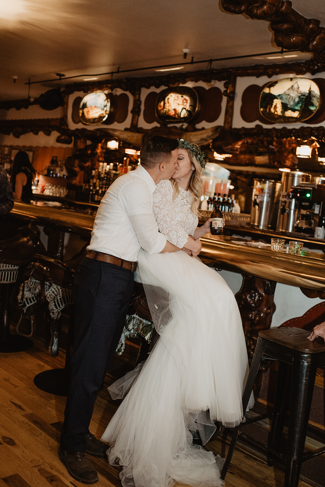 bride and groom sitting at the Cowboy Bar and kissing after they elope in the Grand Tetons
