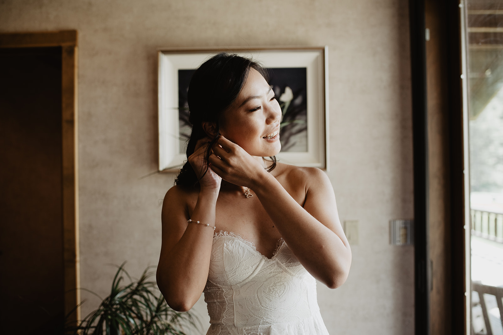 bride putting on her wedding day accessories next to a bright window in her bridal suite for her Jackson Hole elopement