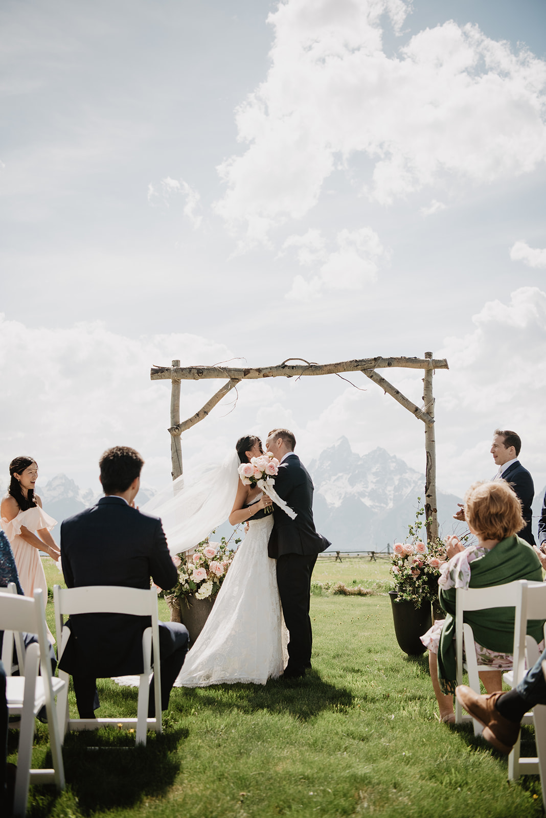 wedding ceremony with a view of the Tetons with the bride and groom kissing at the end of the ceremony