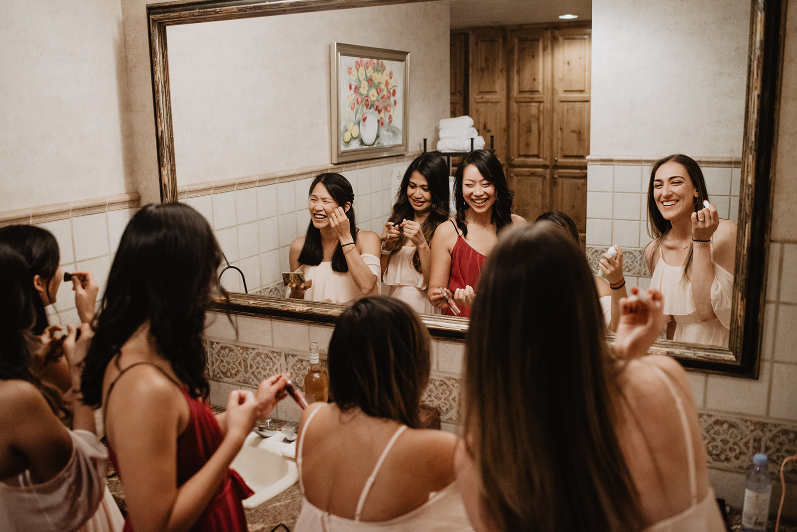 bride and her bridesmaids gettign ready in front of the mirror in their matching pajamas