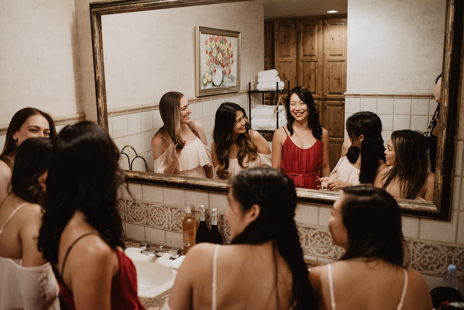 bride and her bridesmaids getting ready together in front of a mirror in a Jackson Hole wedding venue as they laugh and smile