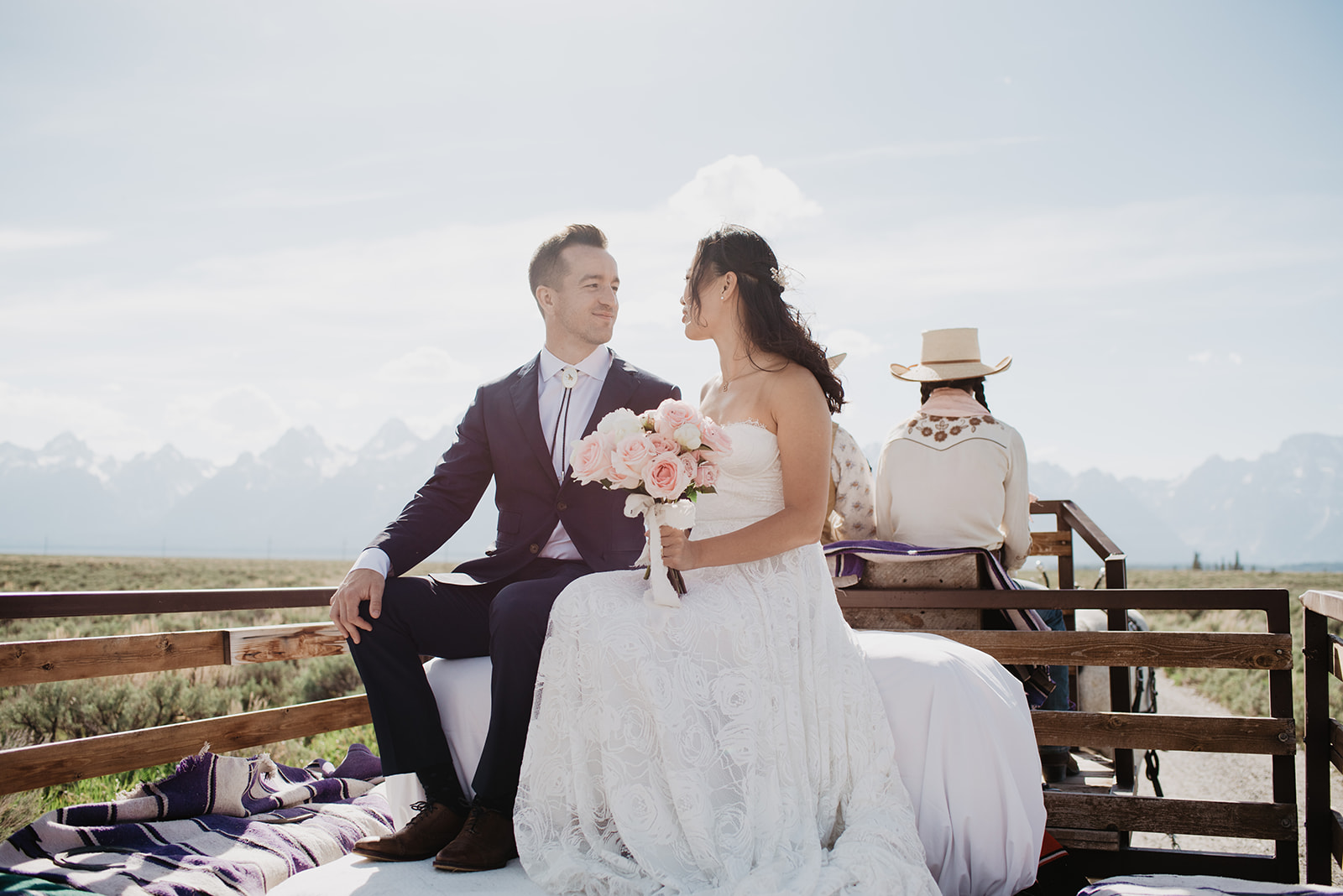 bride and groom at Lost Creek Ranch in Jackson Hole riding on a horse drawn wagon as they look into each others eyesromantically