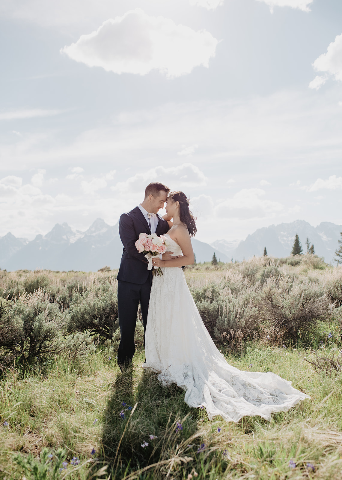 bride and groom embracing in the Tetons in a sage brush field for their Jackson Hole destination wedding