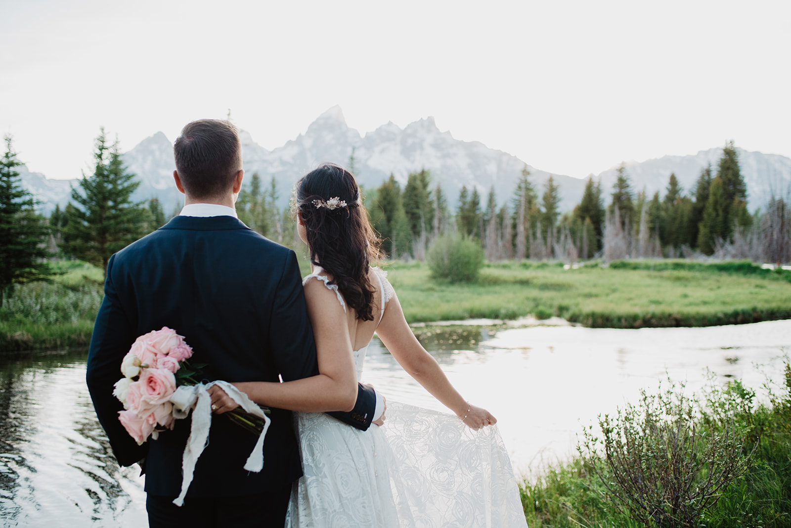 bride and groom facing away from the camera and looking at the Tetons mountains