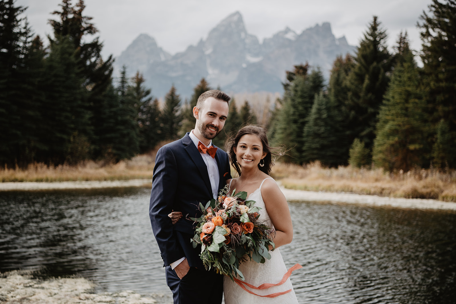 Jackson Hole bride and groom holding each other as they smile at the camera with the Grand Tetons in the distance