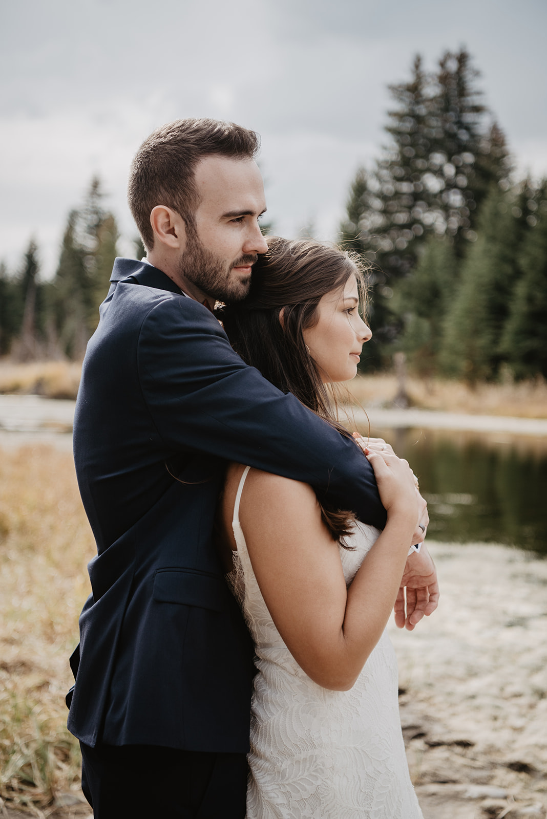 groom holding his bride around the shoulders as he stands behind her