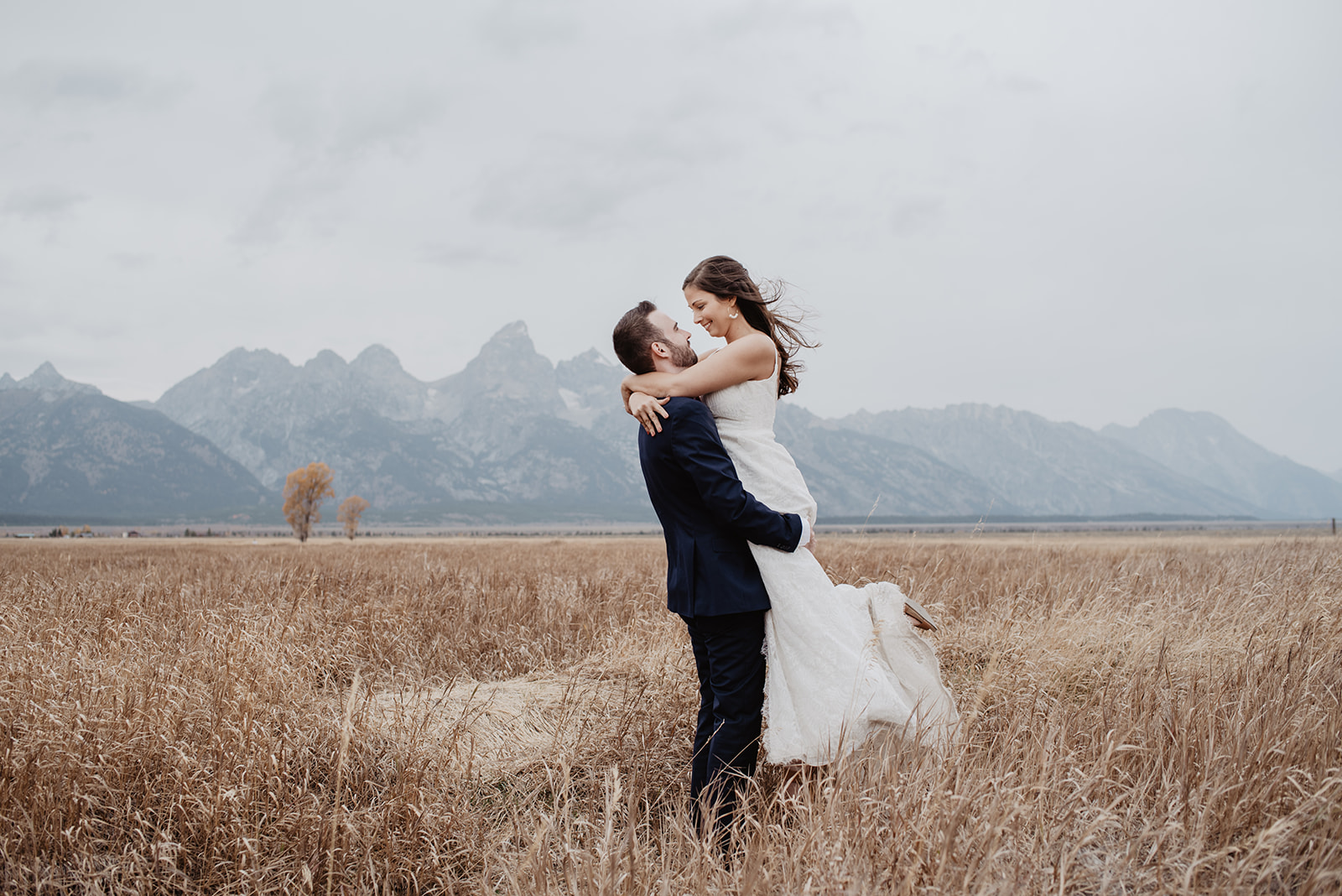 Jackson Hole outdoor wedding photos with groom lifting up his bride in his arms