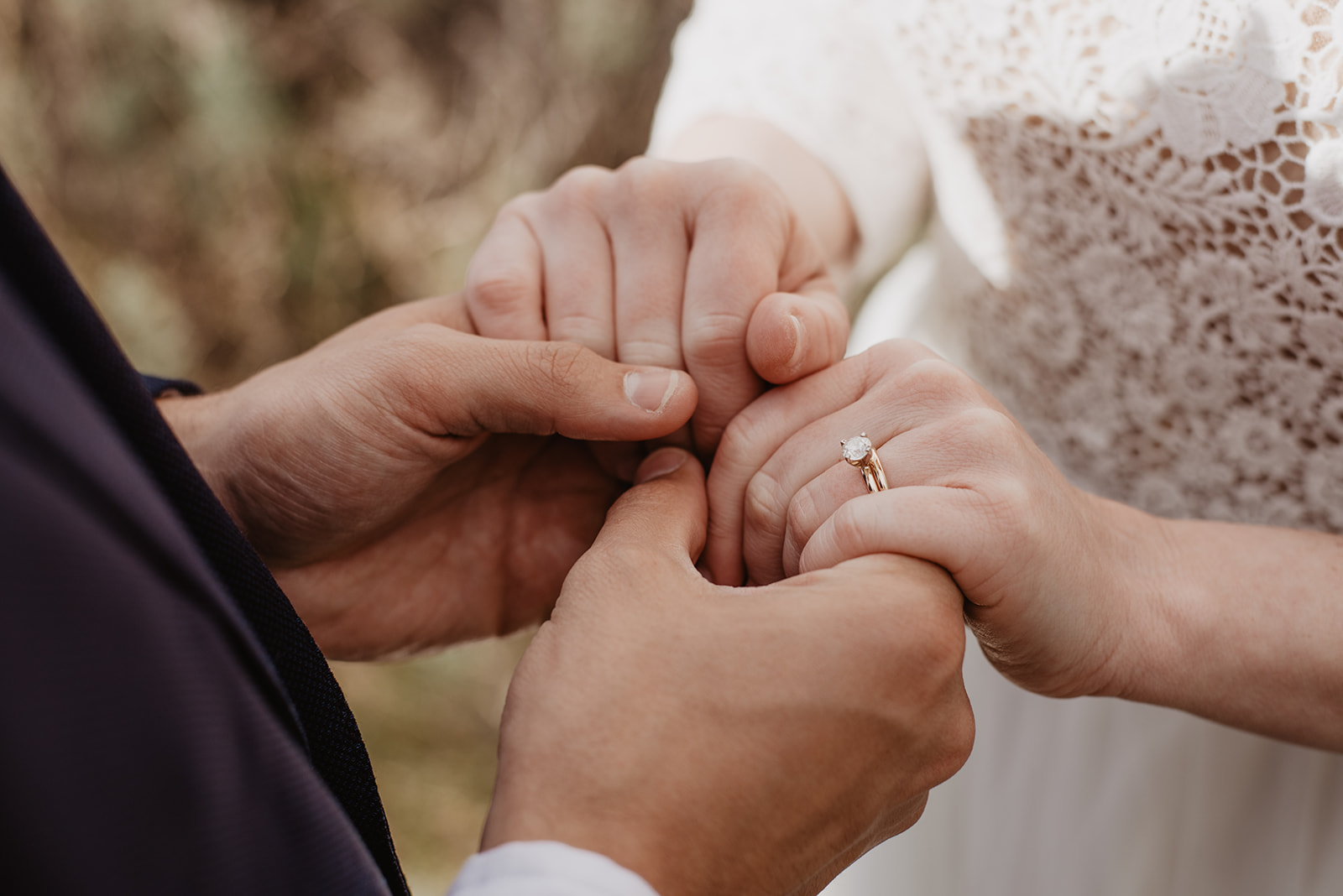 bride and groom holding hands for a detail wedding photo of their wedding rings