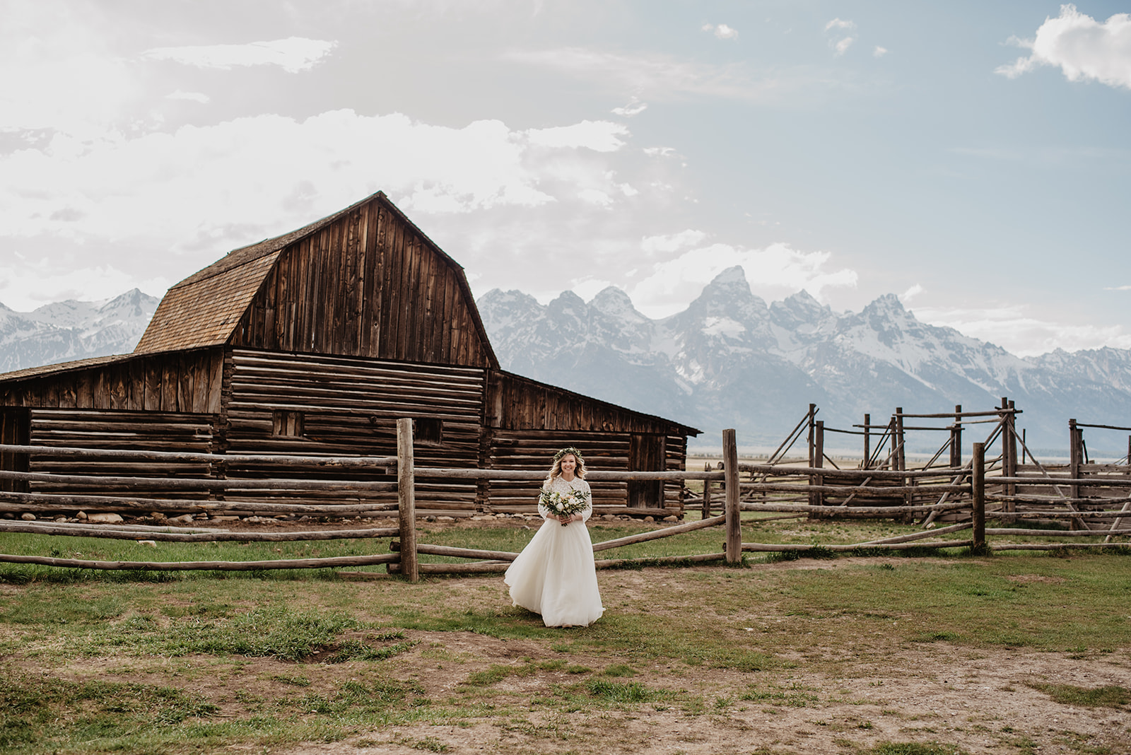 bride walking in front of an old historic barn in the mountains for her wedding photos with Jackson Hole wedding photographers