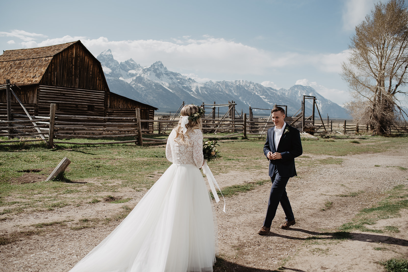 Grand Teton first look with groom turning around to see his bride for the first time at Mormon Row with a barn and mountains in the distance captured by best Grand Teton Wedding Photographer