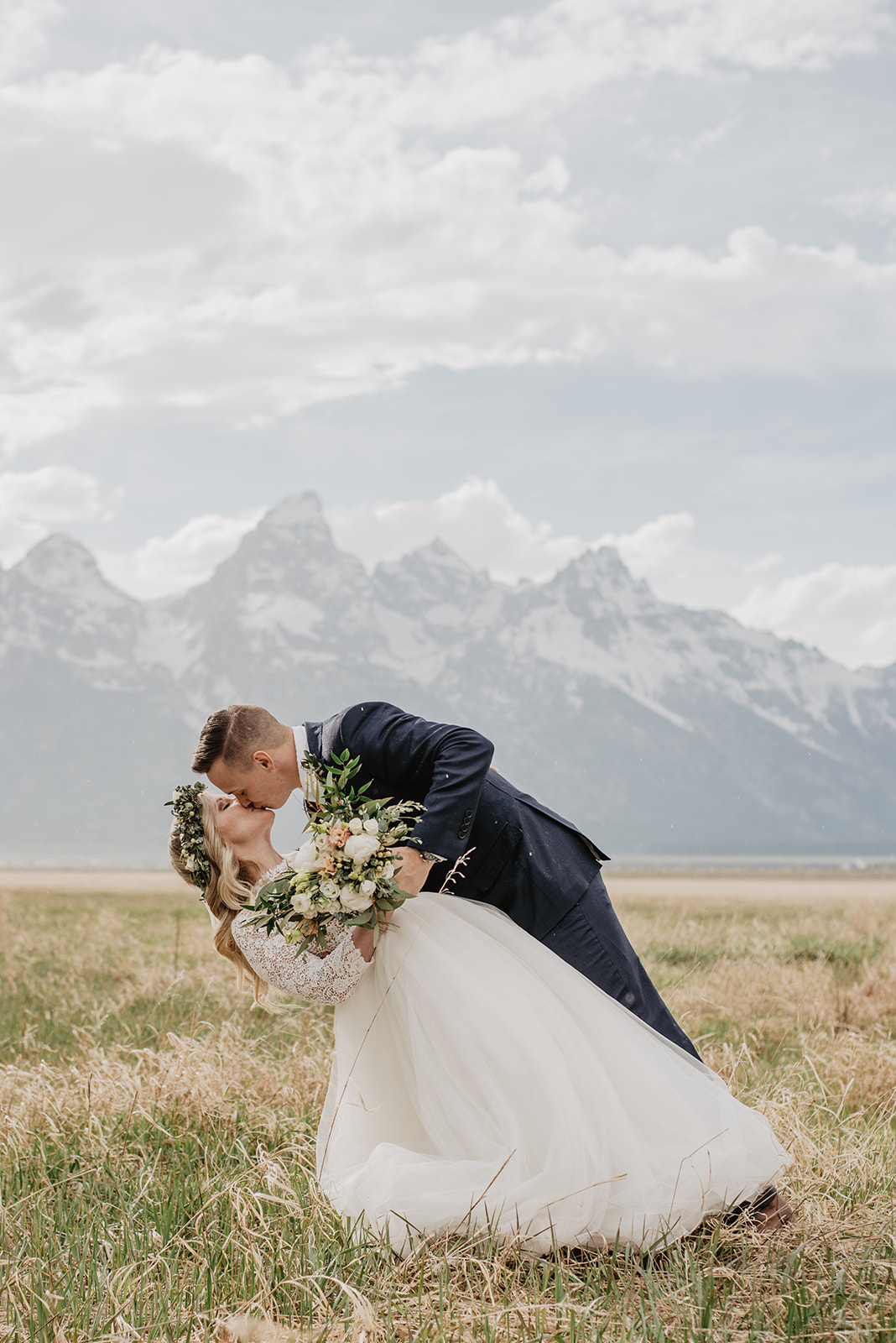groom dipping his bride backwards and kissing her passionately in front of the Tetons taken by Jackson Hole wedding photographers 