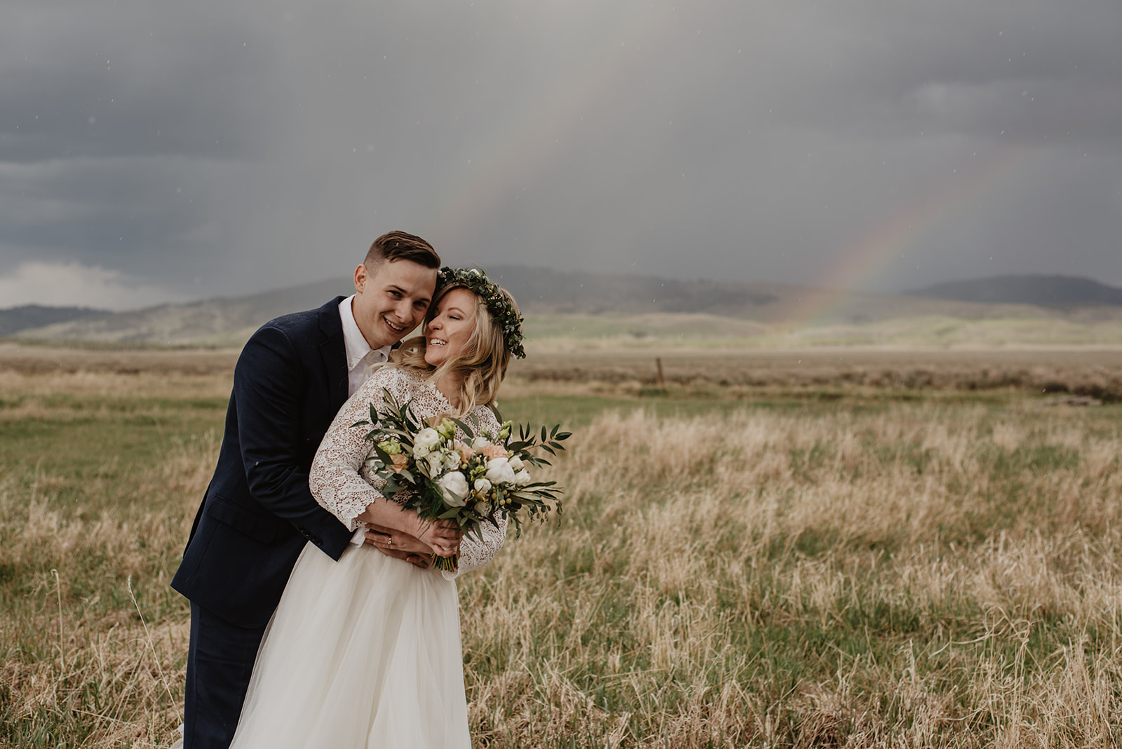 groom hugging bride from behind with a double rainbow behind the couple captured by best Grand Teton Wedding Photographer