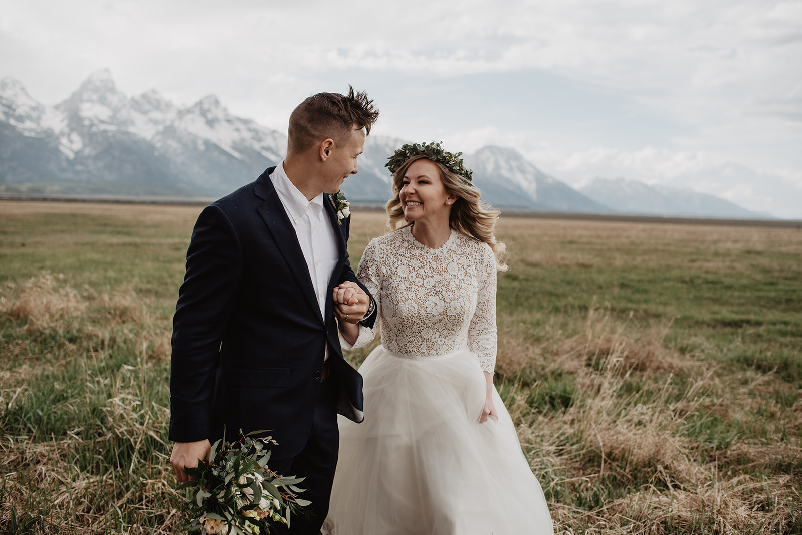 bride laughing as she holding her grooms arm and they lightly run through the Grand Tetons for their spring elopement
