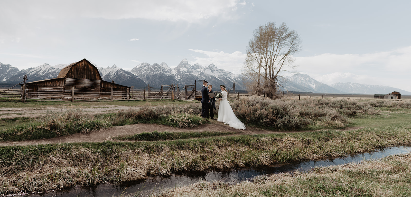 wide shot of bride and groom standing with their officiant at Mormon Row in the Tetons captured by best Grand Teton Wedding Photographer