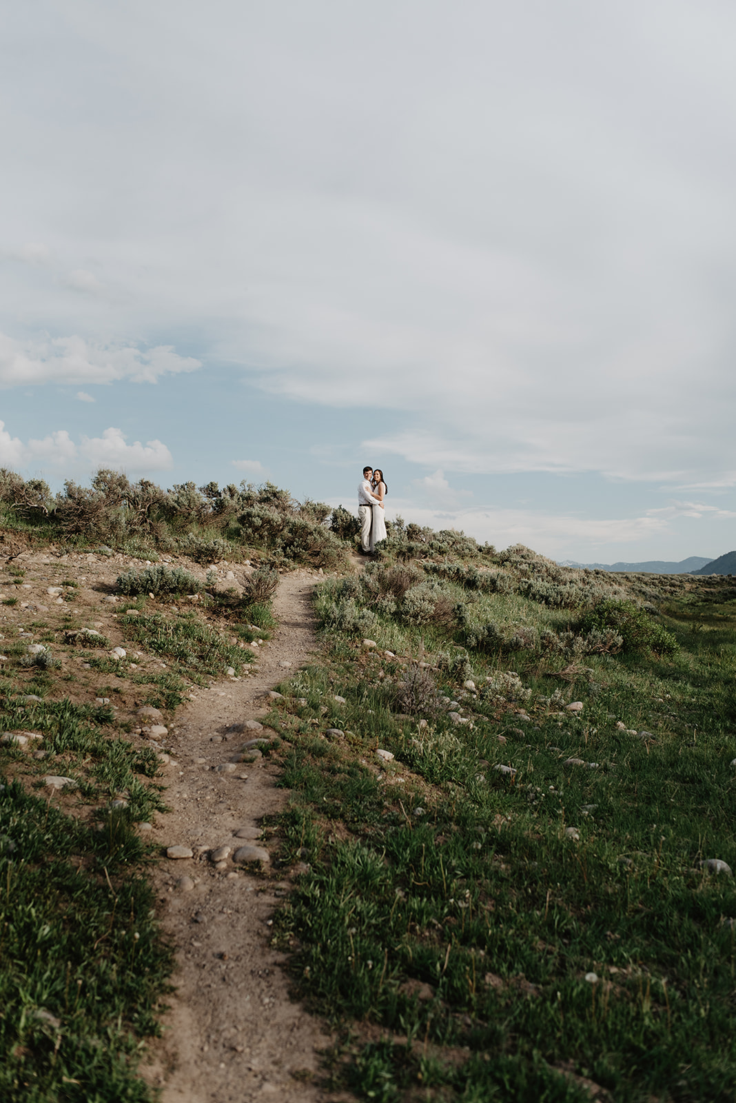 Bride and groom standing on a trail that scales a hillside