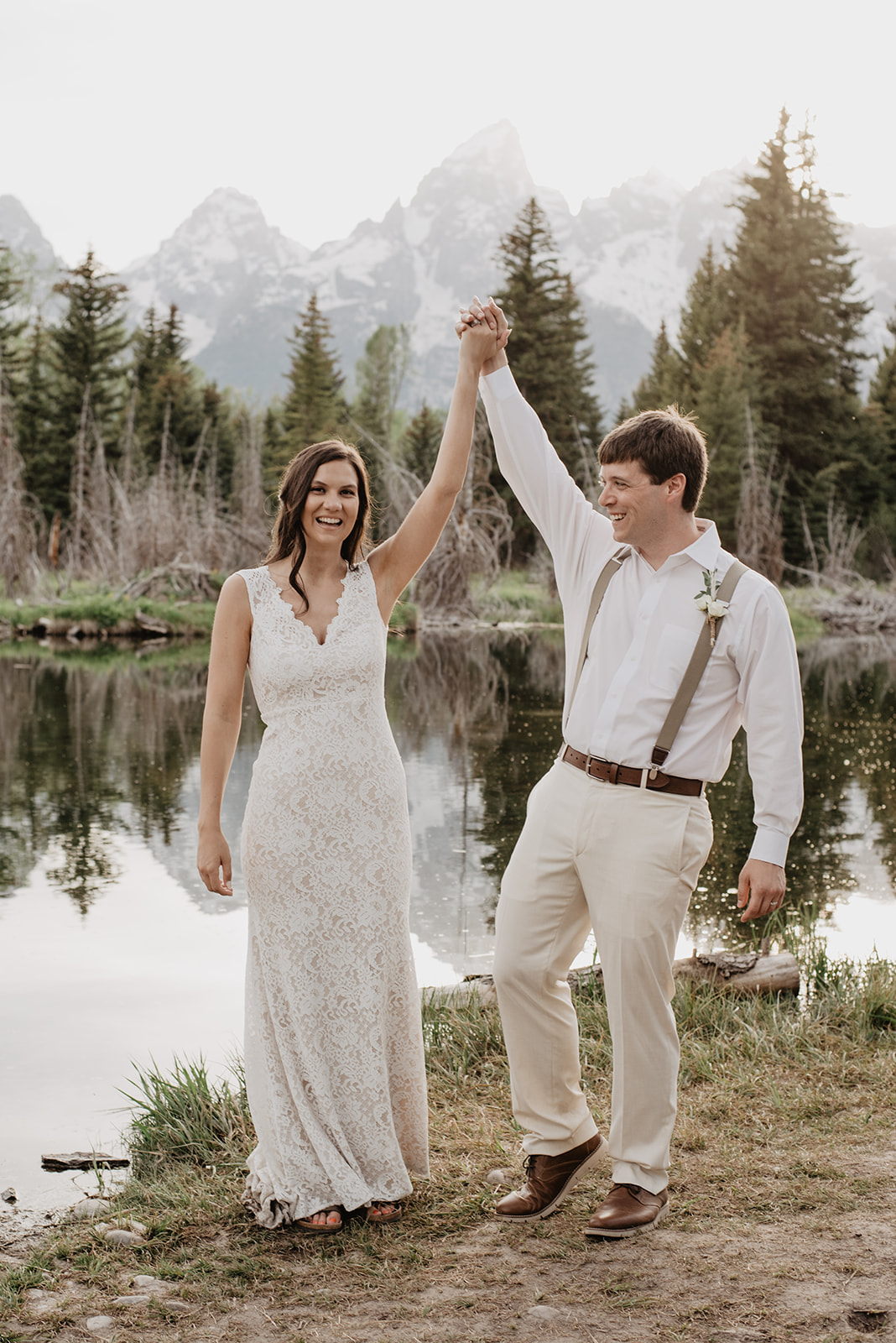 bride and groom holding hands in the air as they smile and celebrate their Jackson Hole elopement