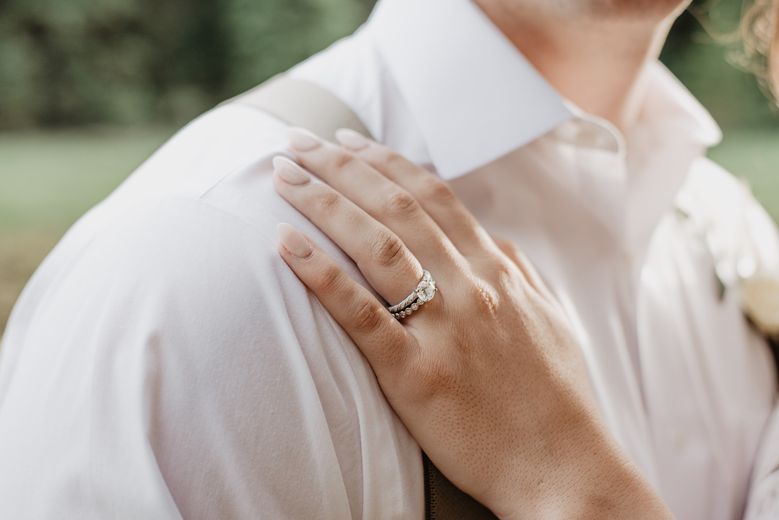 engagement ring on brides hand as she holds onto her grooms chest for their bridal session in the Tetons photographed by Jackson Hole wedding photographer 