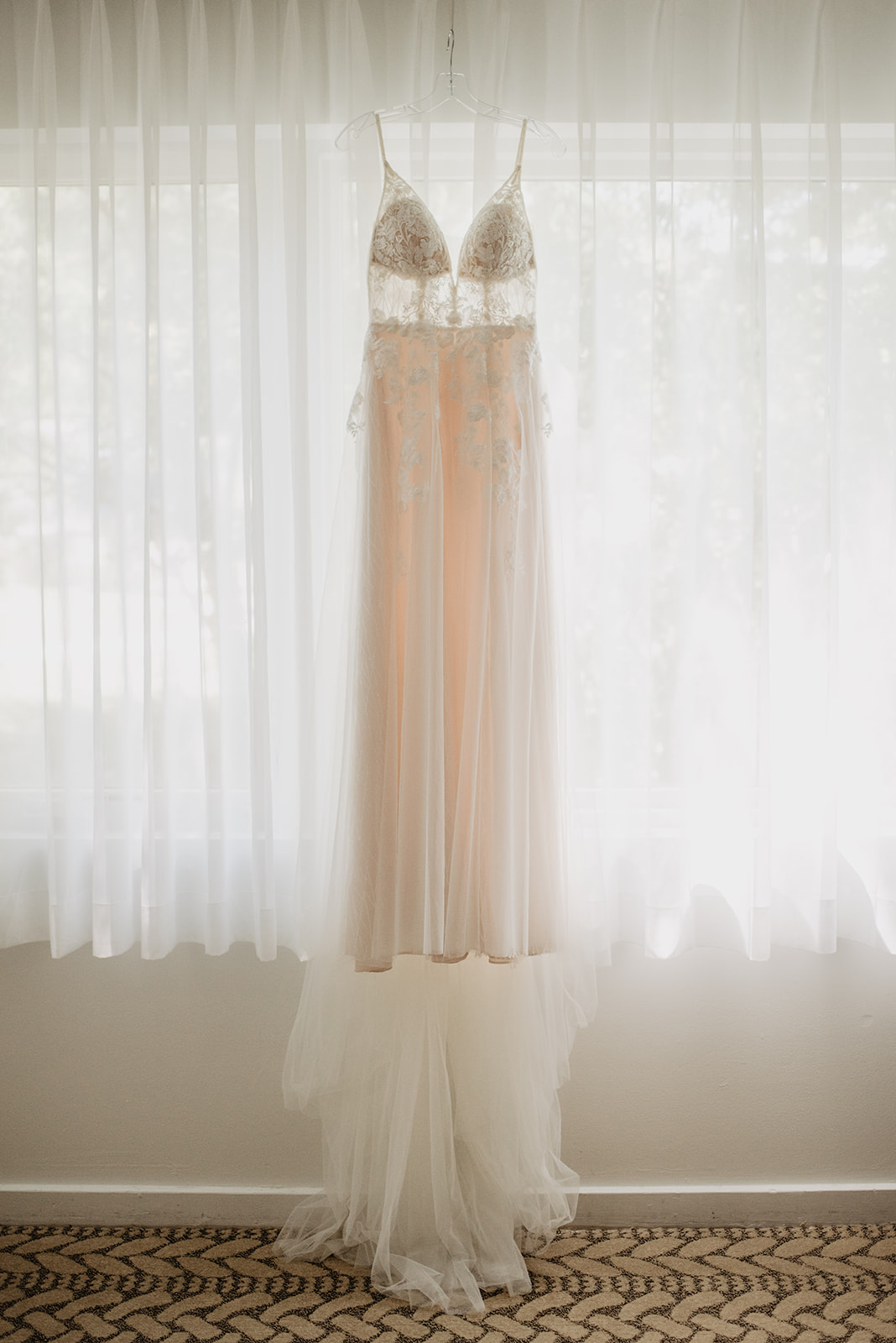 detail shot of lace and sequence wedding dress hanging in the window in a luxury suite in Snow King resort
