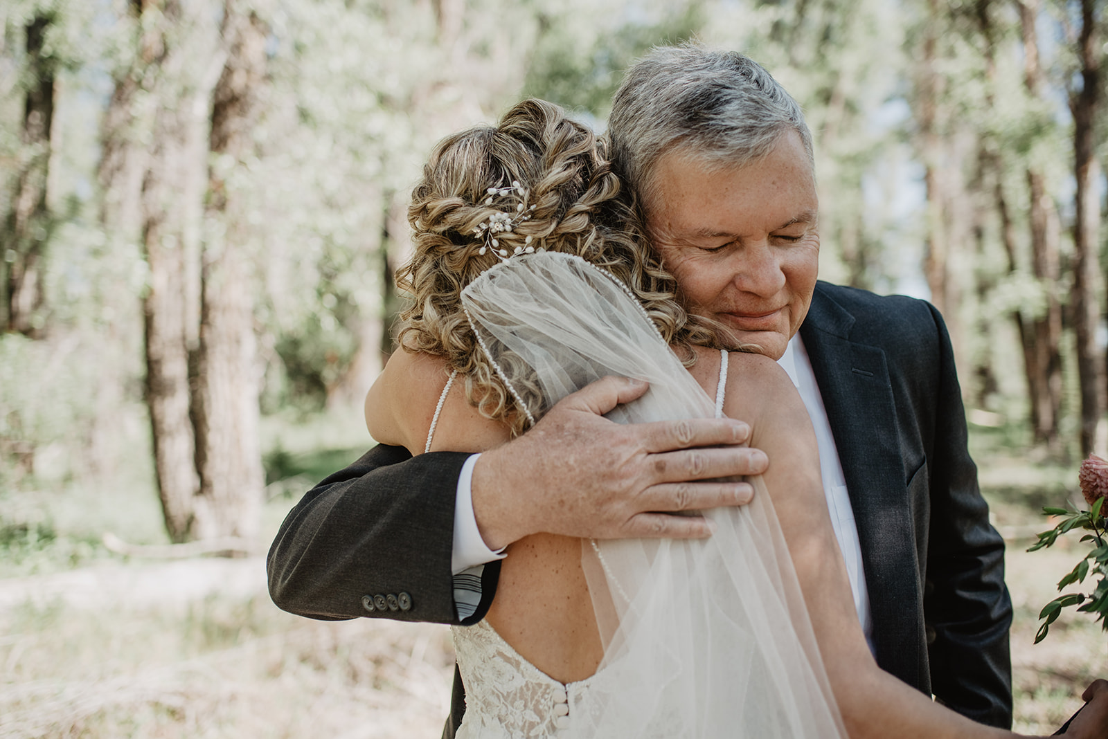 father of the bride hugging his daughter after he has a first look with her at her Grand Teton summer elopement