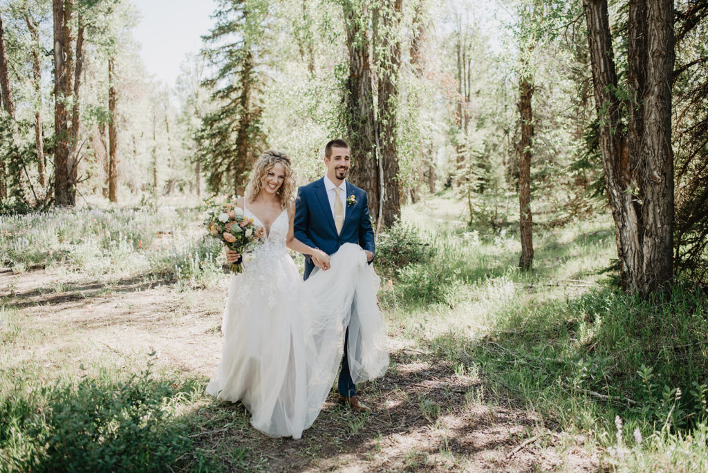 bride and groom walking through the woods for their Grand Teton elopement while staying on a trail