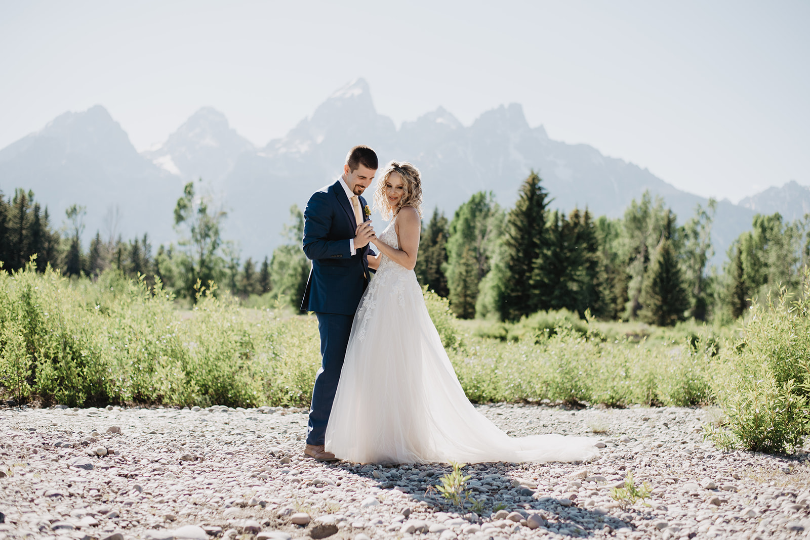 bride and groom holding hands and dancing for their Grand Teton summer elopement with the mountains behind them in the distance