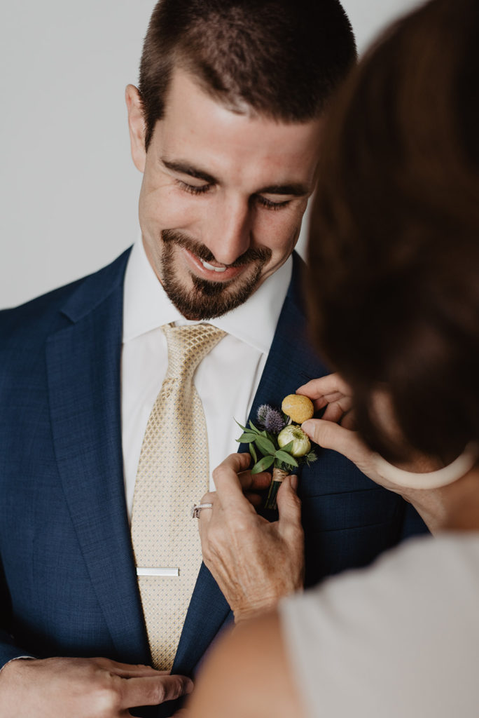 groom getting ready while putting on his tie with Jackson Hole wedding photographer 