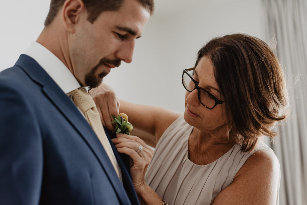 Jackson Hole wedding photographer captures mother of the groom helping him get ready the morning of his elopement