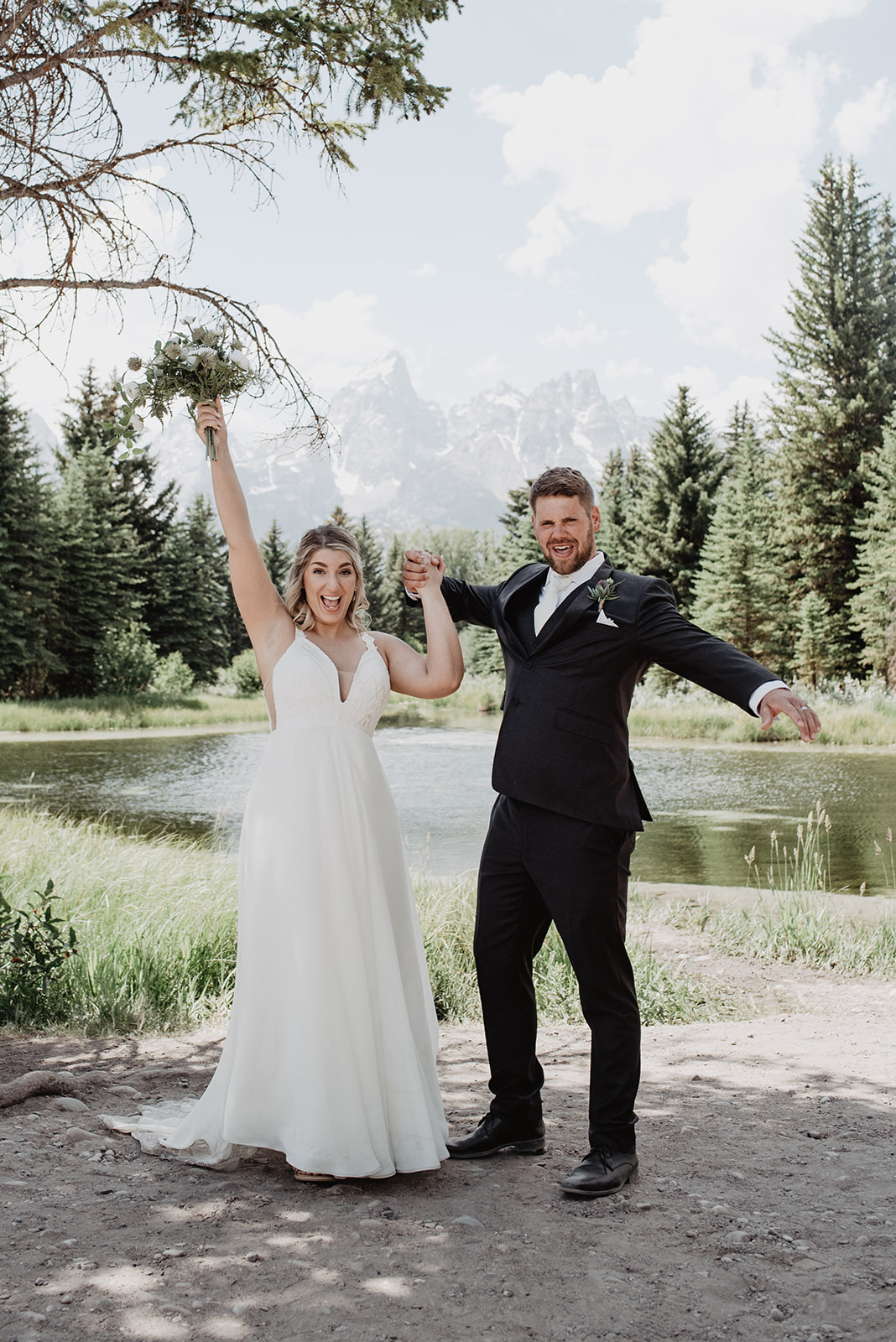 bride adn groom with their hands in the air celebrating their marriage int eh Grand Tetons