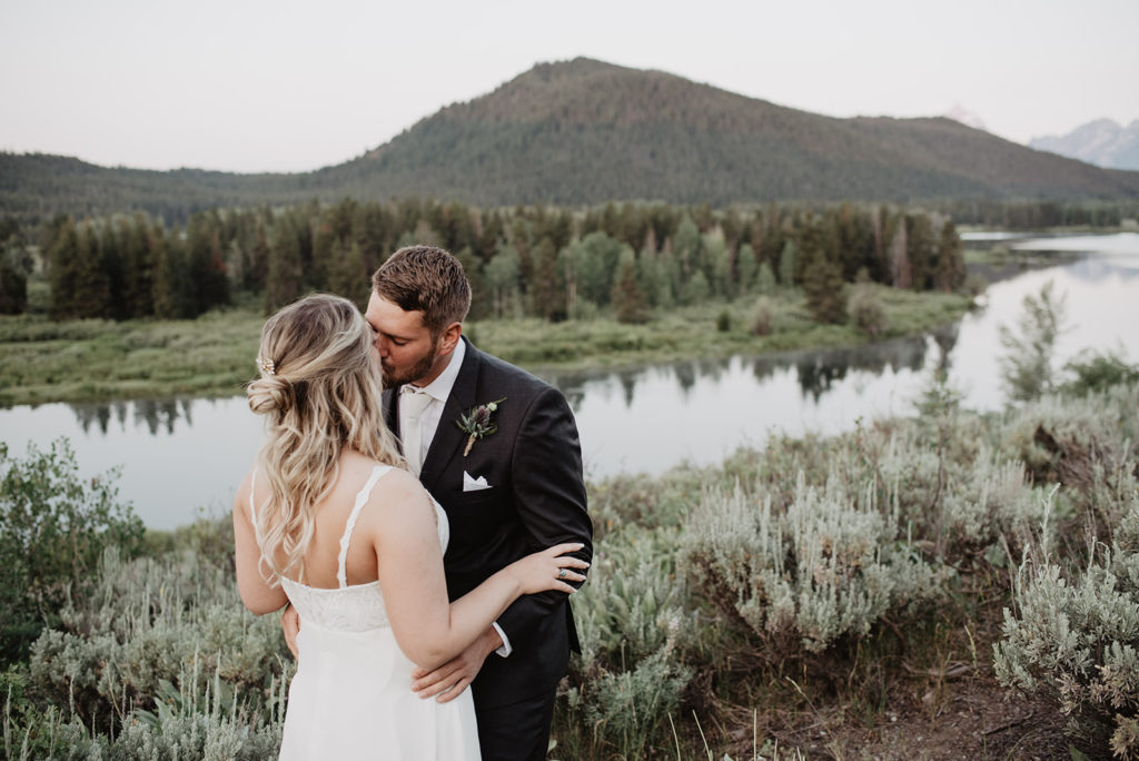 Grand Teton elopement with bride and groom kissing at their sunrise session next to a river 