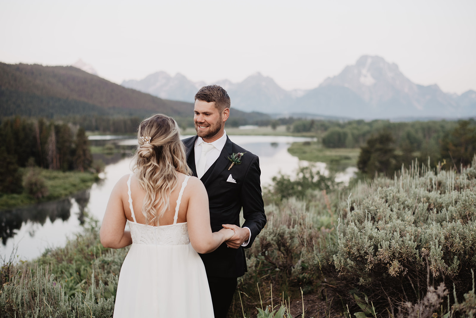 sunrise first look in Grand Tetons with groom holding his bride as he sees her for the first time