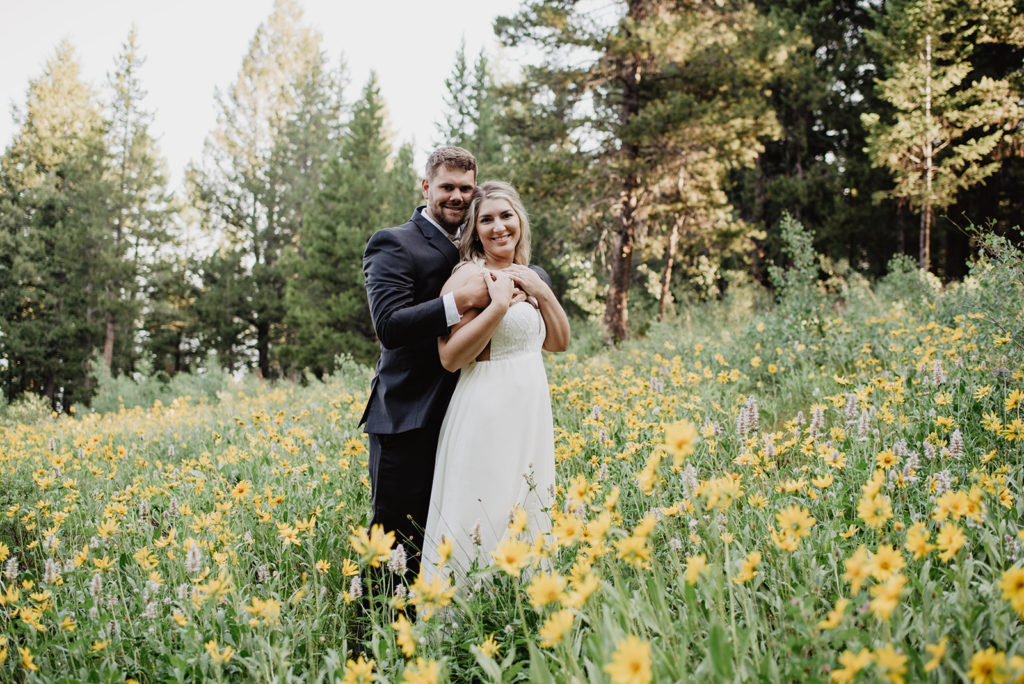 spring wedding in the mountains with bride and groom embracing in a field of yellow flowers