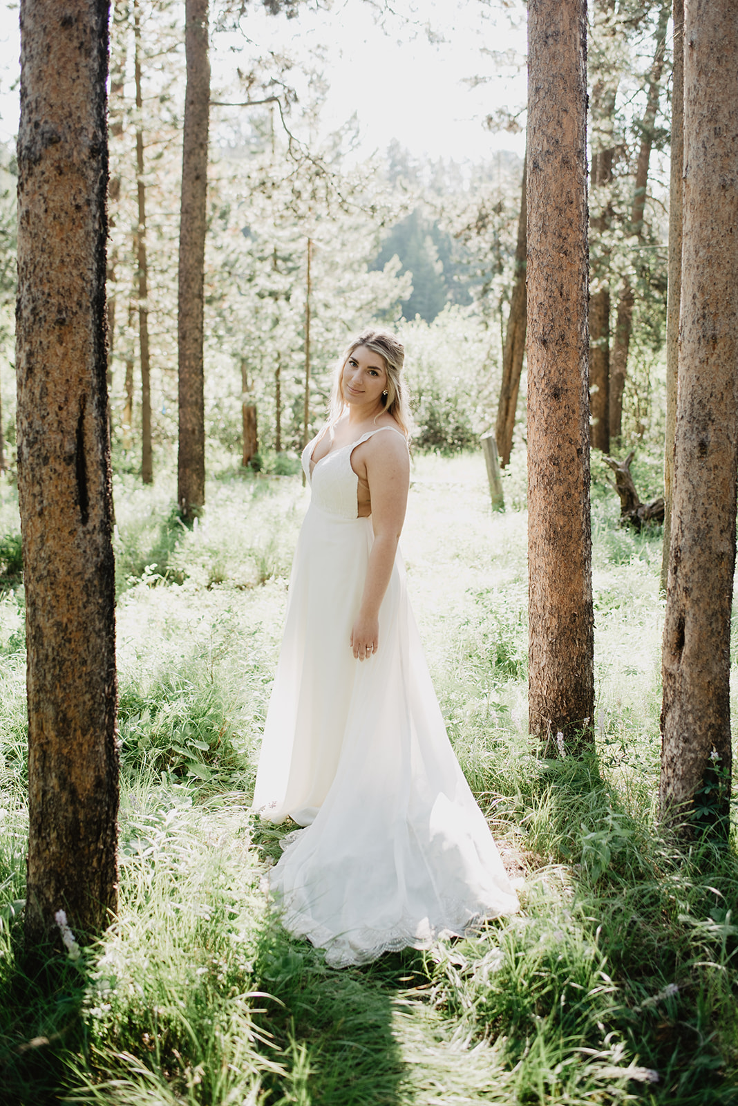 bridal portraits of bride in a meadow surrounded by trees for her Jackson Hole elopement in the summer