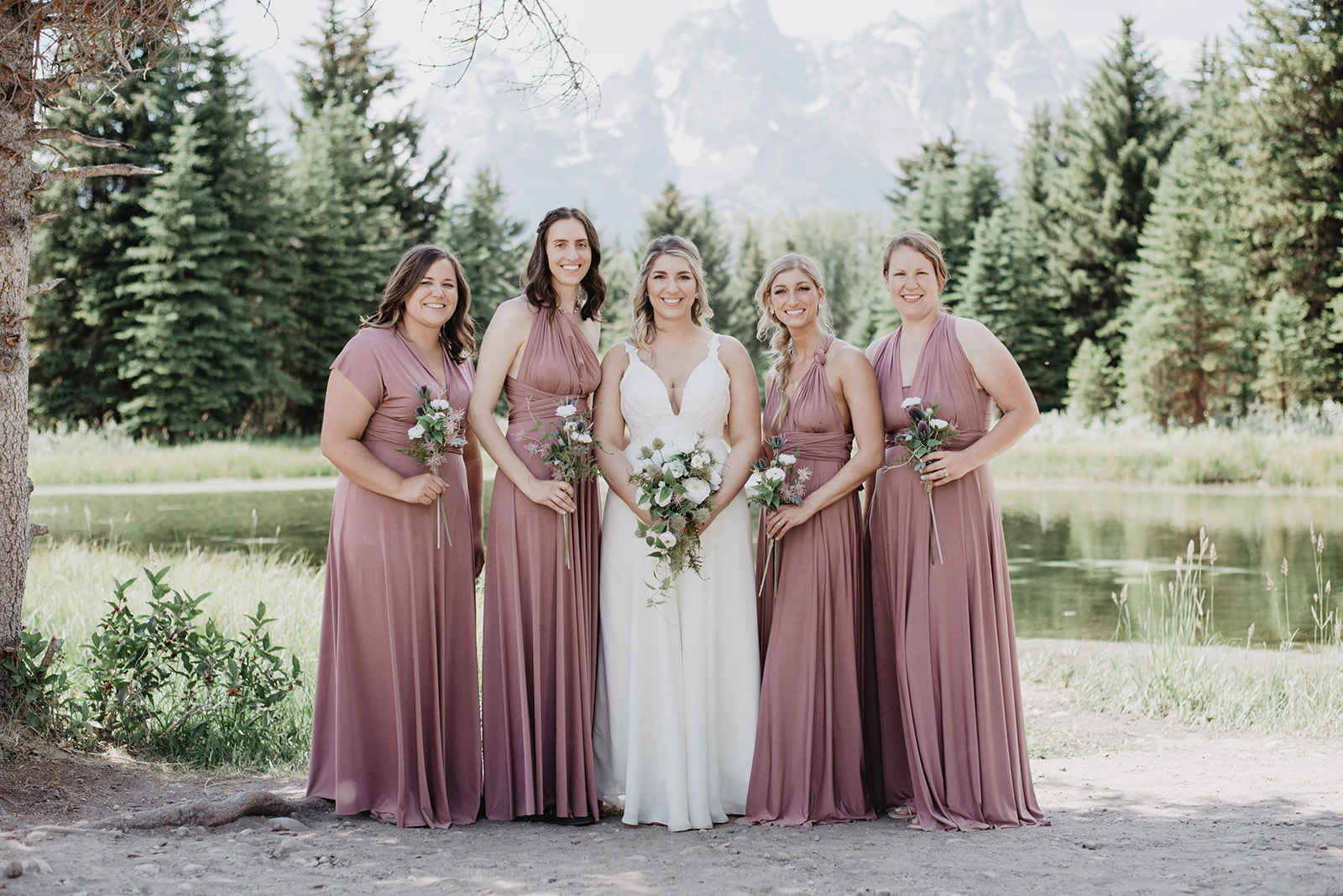 bride with her bridesmaids as they stand together and smile with the Tetons behind them in the distance for elopement photos
