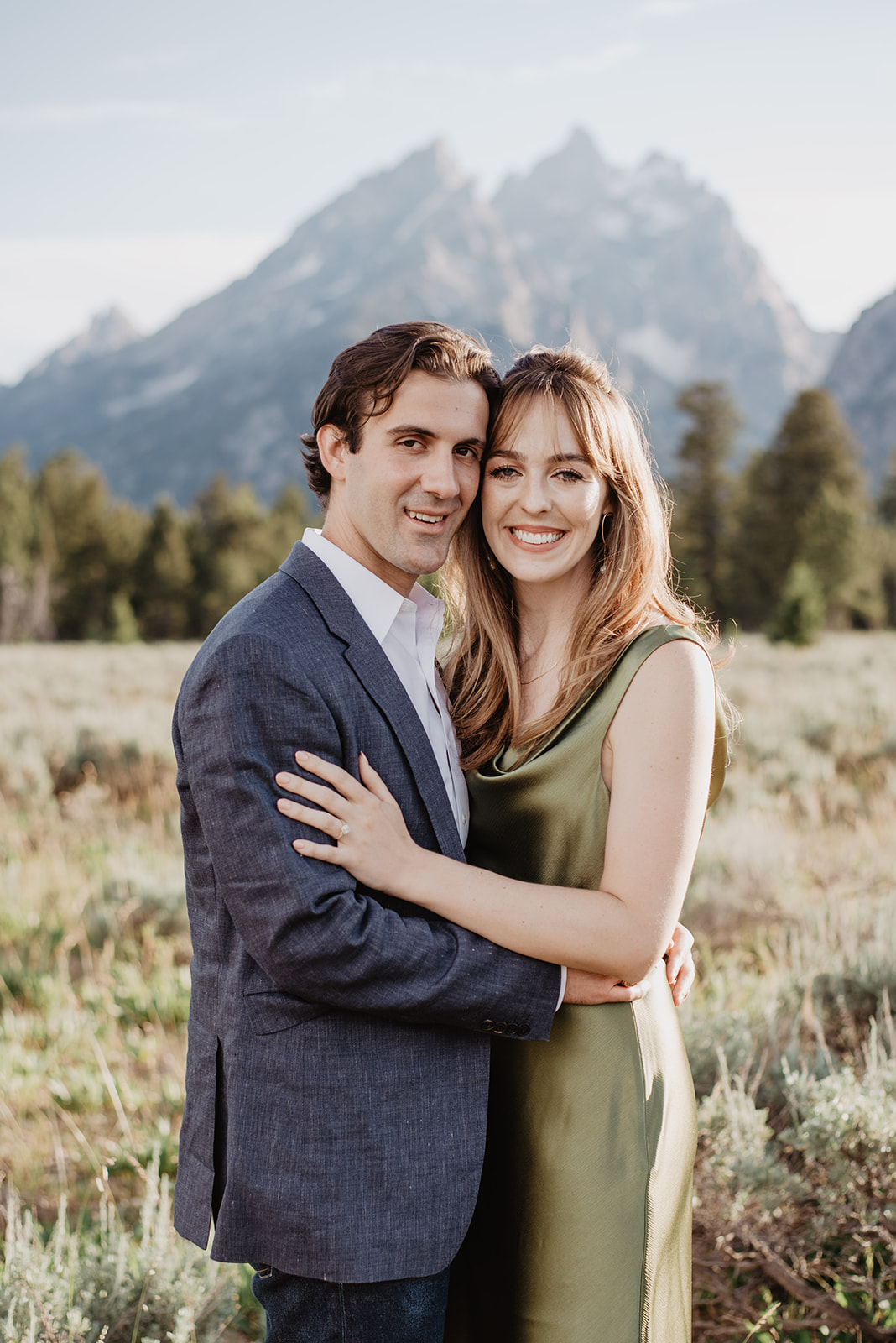 formal engagement portraits with man and woman in elegant engagement outfits holding each other and looking into the camera as they smile