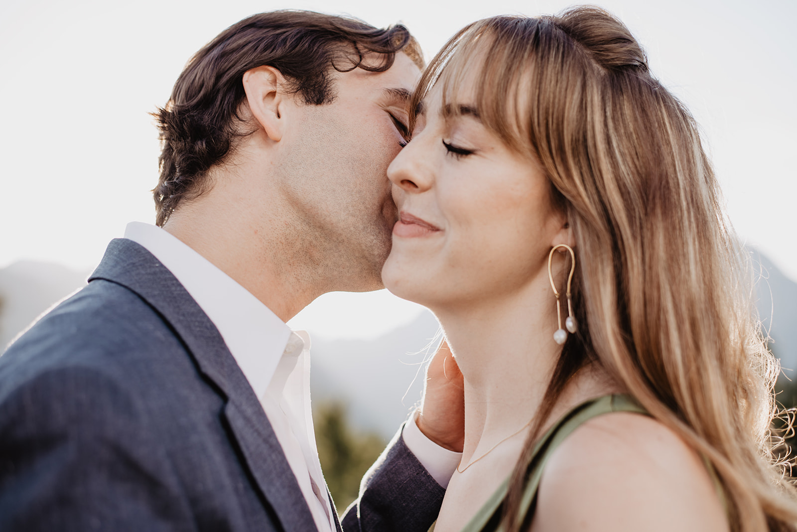summer engagement photos in Jackson Hole with man and woman embracing as the kisses the womans face