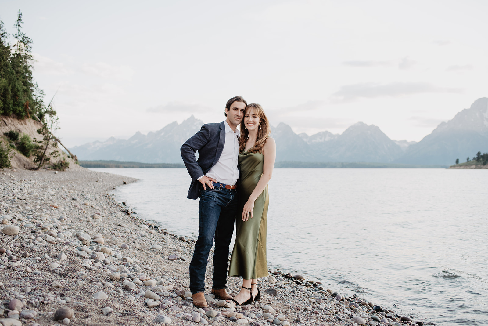 man and woman standing together at a lake in Jackson Hole for their engagement photos
