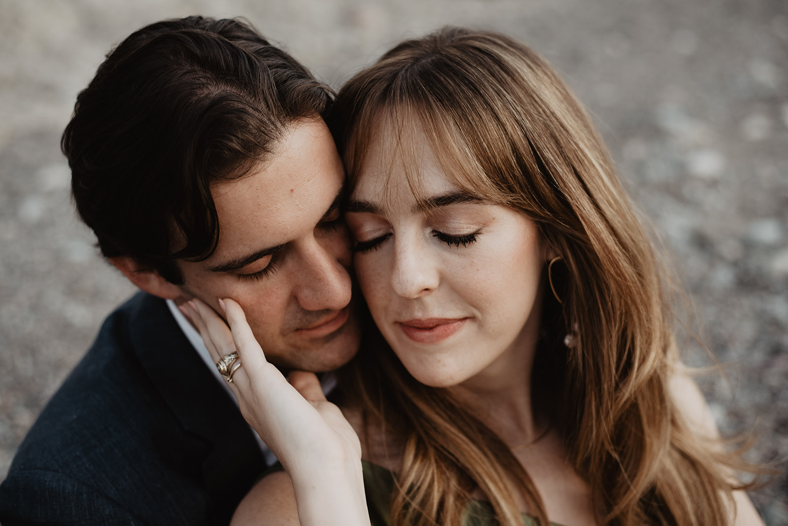 engagement portrait with man and woman holding each other closely as the woman holds the mans cheek