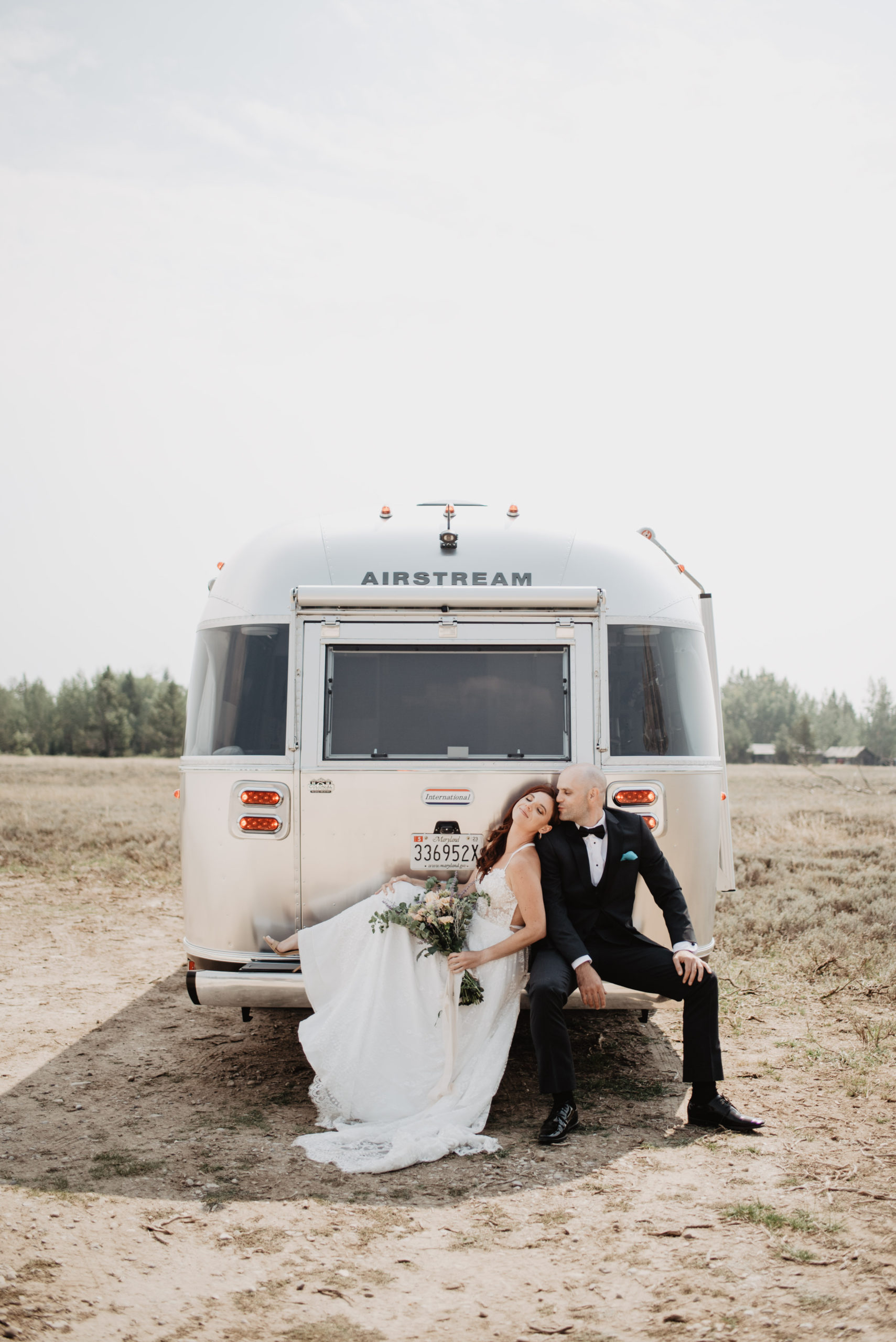 epic Grand Teton elopement shot with bride and groom sitting on the back of their airstream for their fall Grand Teton wedding