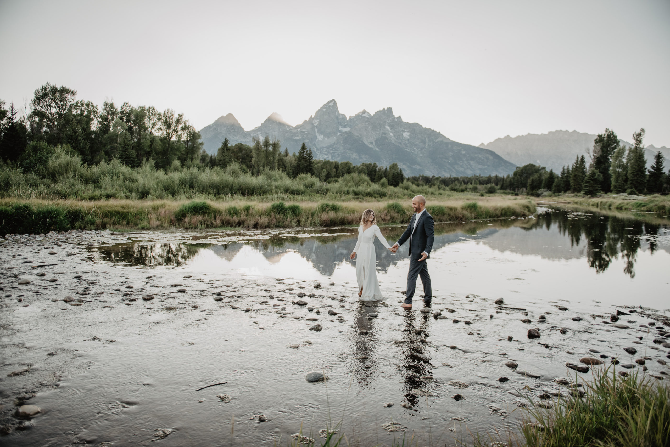 Grand Teton National Park sunset wedding photos with bride and groom holding hands and walking through a river together