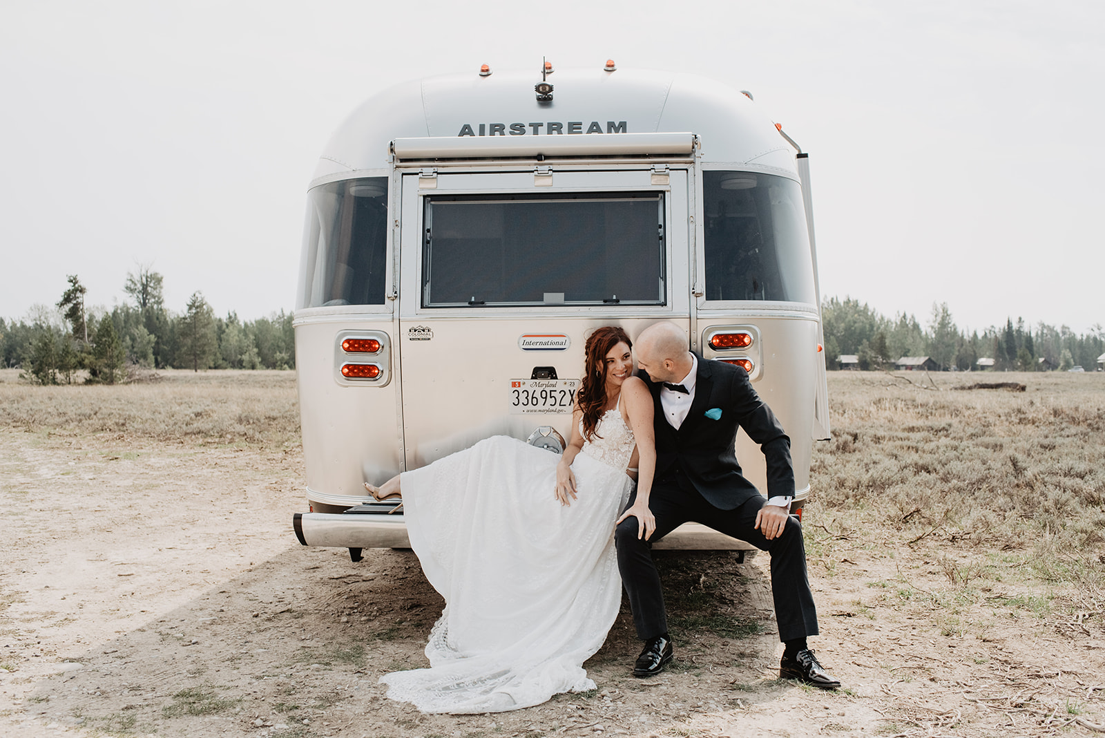 bride and groom sitting on the back of their airstream together in their wedding attire int he Grand Tetons