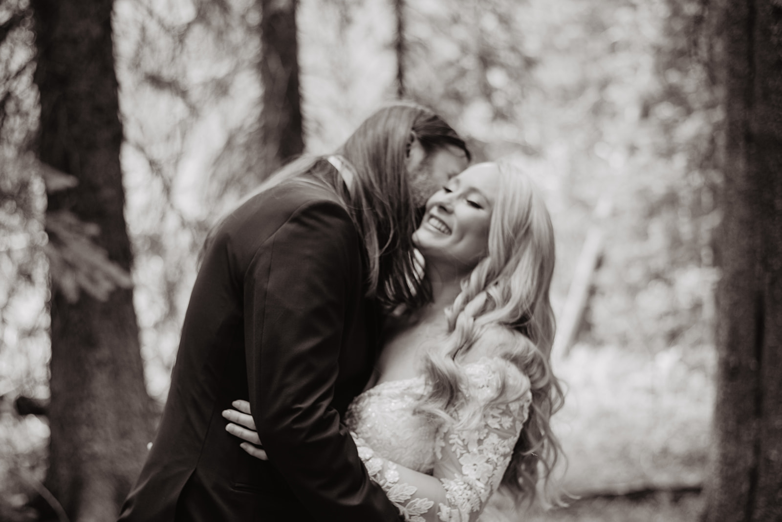 black and white weddin gpictures with groom kissing his brides neck as she giggles in the woods in the Tetons with Jackson Hole wedding photographer 
