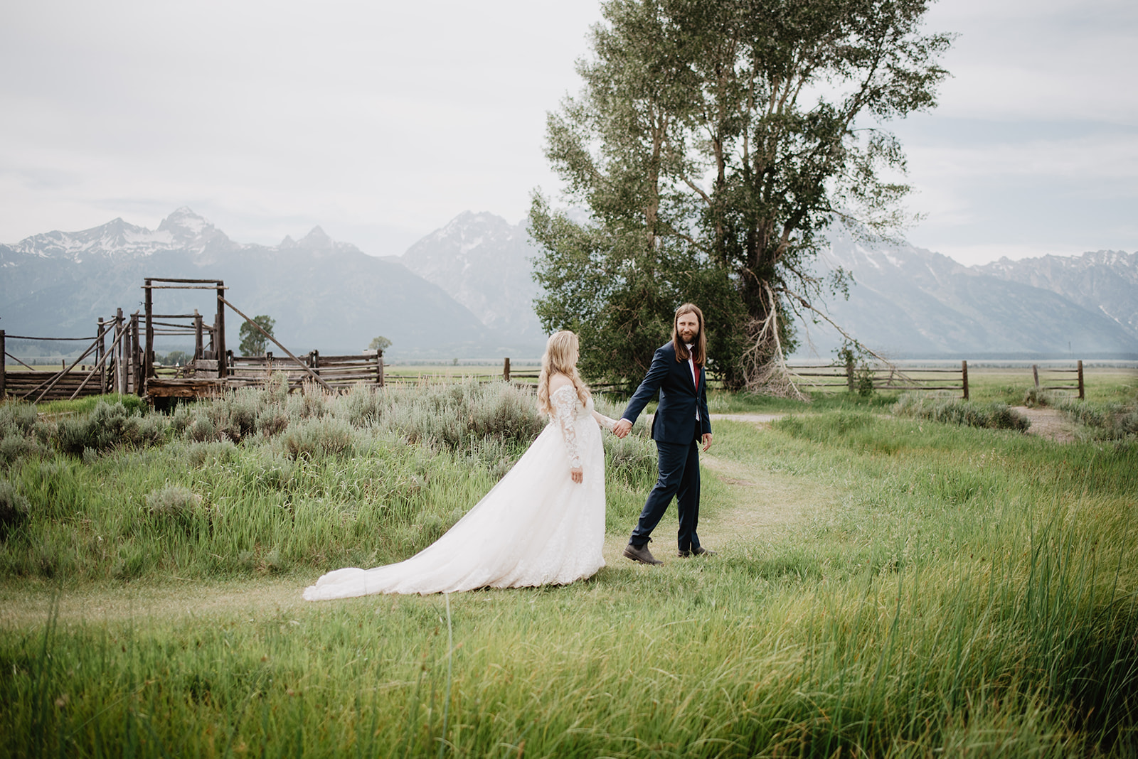 outdoor weddin gin Jackson Hole with groom holding brides hand as he leads her down a trail