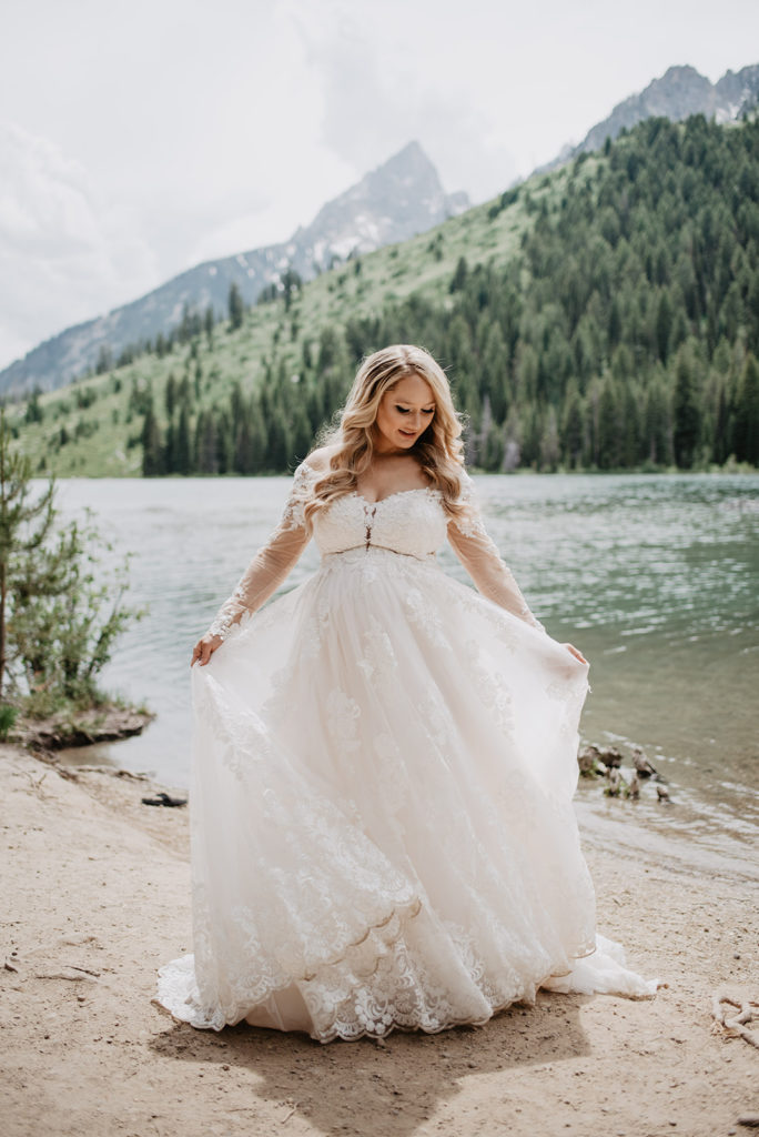 Jackson Hole wedding day with bride dancing and twirling in her wedding dress on the beach of String Lake