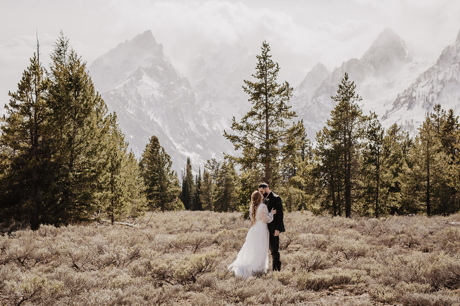 bride and groom embracing and kissing in the mountains woods captured by Jackson Hole wedding photographers