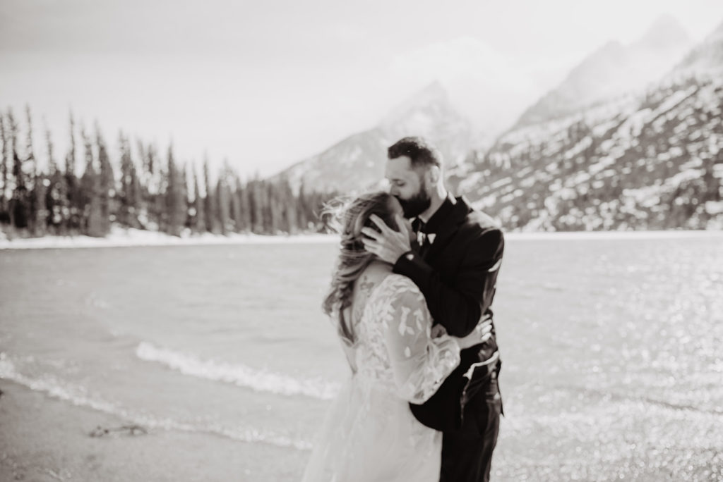 groom holding his brides head while kissing her head and she holds his torso at String lake for their Jackson Hole wedding photographed by Jackson Hole photographers